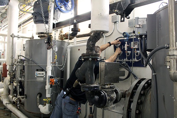 A worker adjusting controls on a large pump.