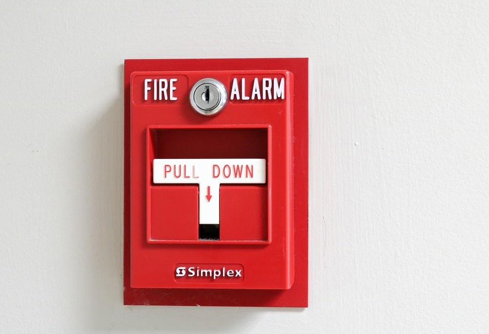 A red fire alarm with a white handle that says pull down