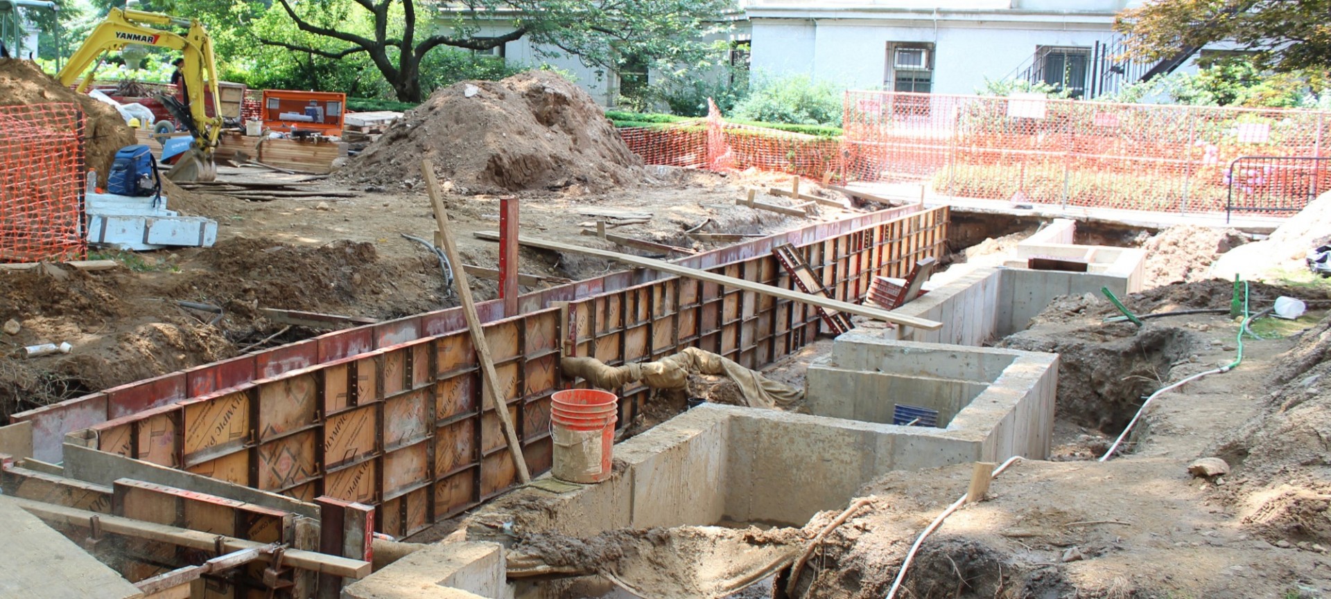 An area excavated lawn with mini concrete walls for construction.