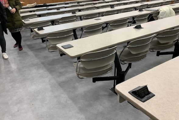 Campus Operations disconnected power to the desks, dismanted all of the furniture, and demolished the previous flooring in order to install new flooring in IAB Room 413. Gray flooring in IAB Room 413 with long rows of desks