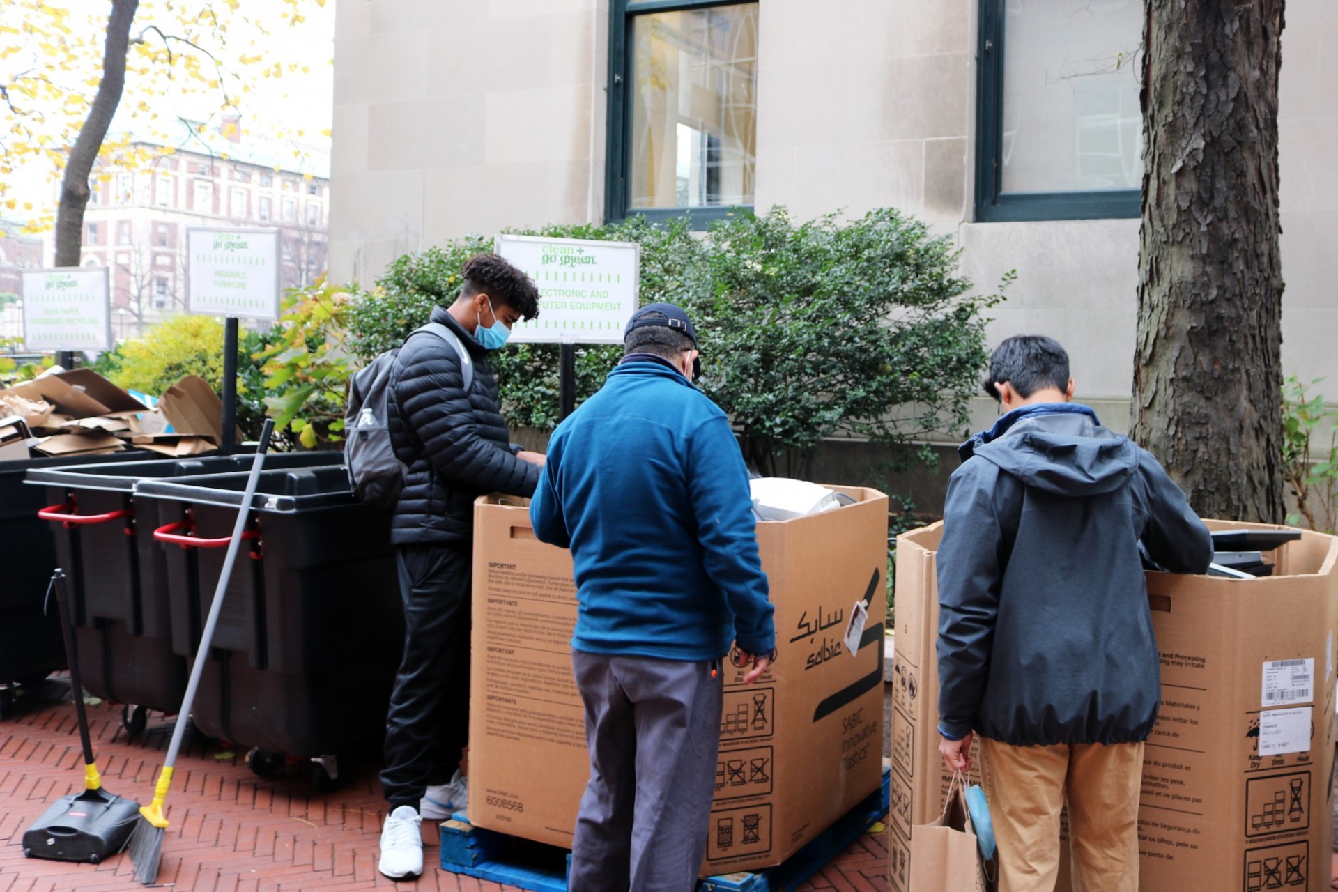 Students check Clean + Go Green bins full of electronics that are next to Butler Library.
