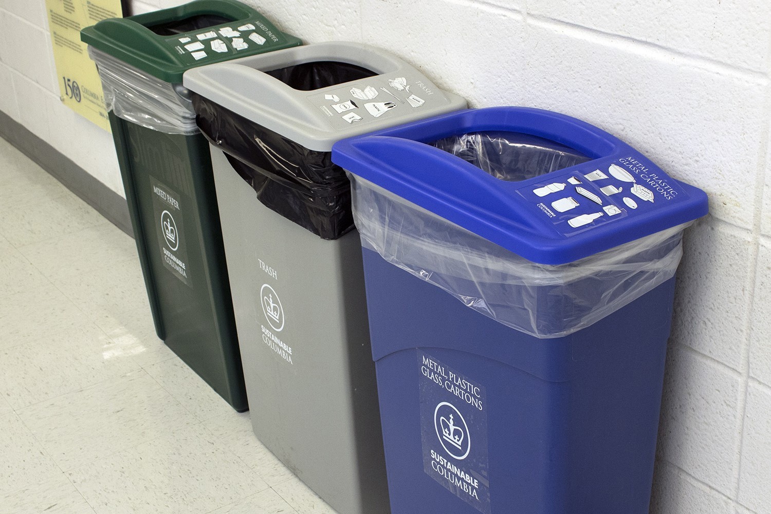 Green, gray, and blue recycling and trash bins sitting next to 