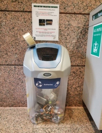A battery recycling bin against a wall