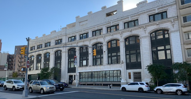 The exterior of Prentis Hall with cars waiting at a stop light in front of the building