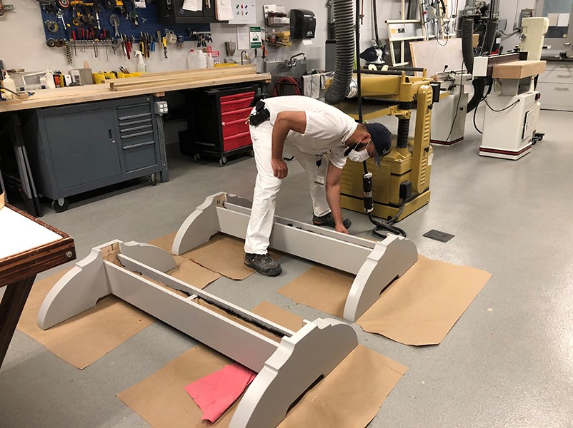 A painter applies a coat of silver paint to the tops and bottoms of the frames.  