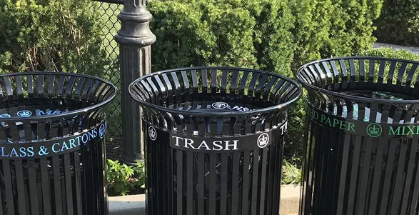Three black bins that are for glass, plastic, and metal; trash; and mixed paper.