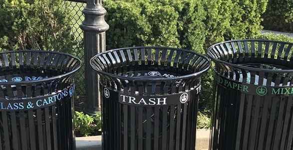 Three black bins that are for glass, plastic, and metal; trash; and mixed paper.