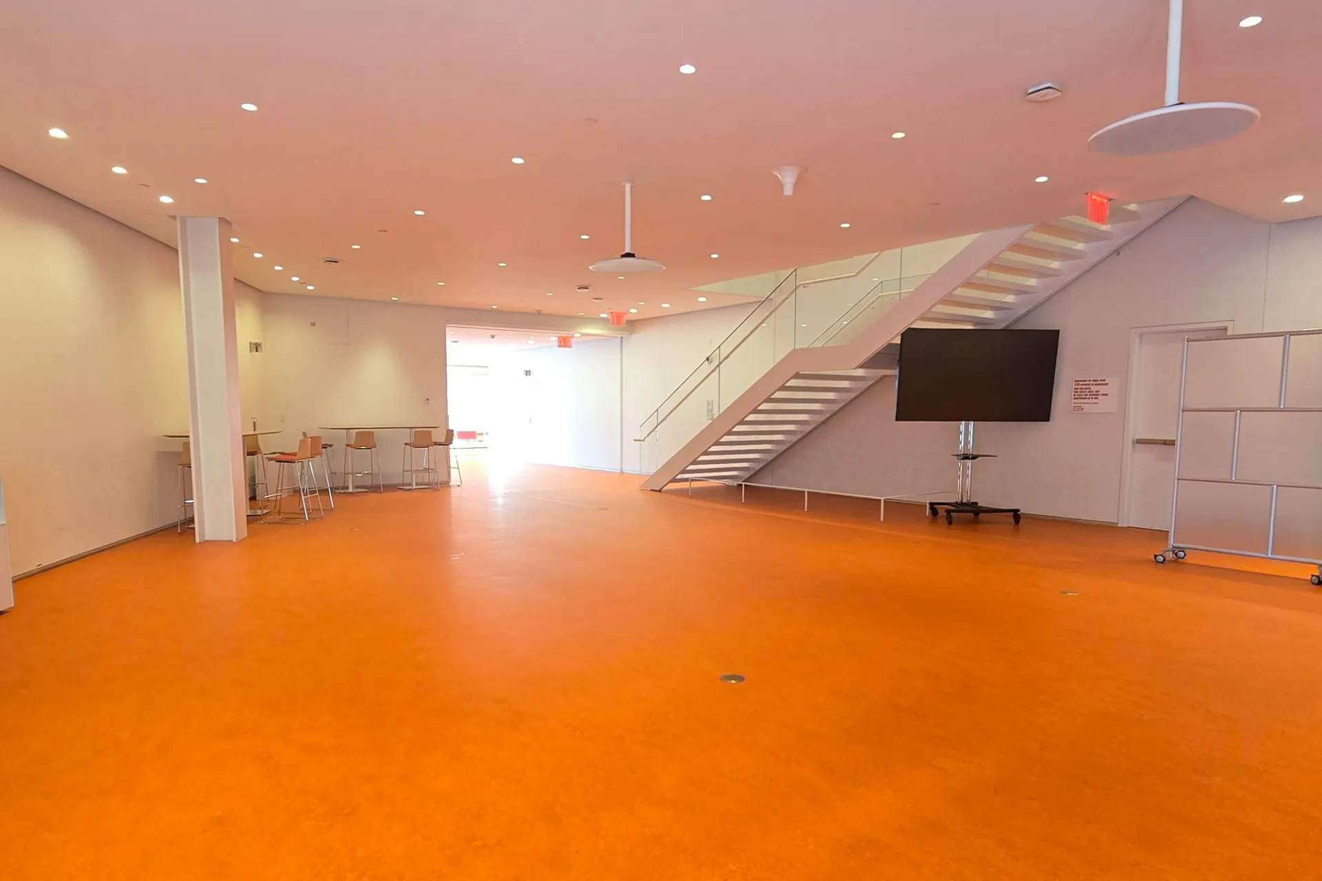 New bright orange flooring that is installed in a open space outside of the auditorium of the Bollonger Forum.