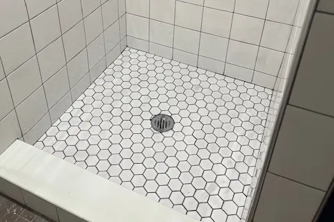 New white hexagon tile flooring inside of a shower.