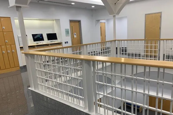An open corridor featuring wooden lockers and two computers against the wall. 