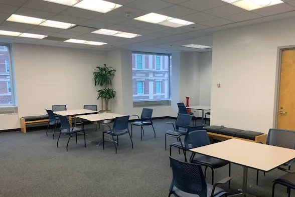 A student lounge room with several tables and chairs inside 